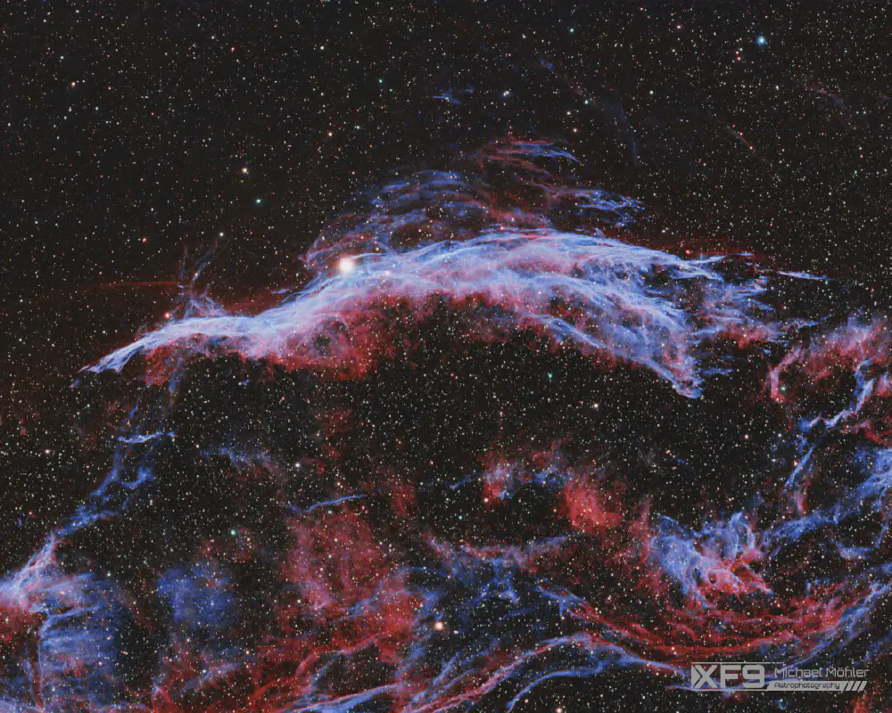 A gas cloud which is mostly red and blue forming a structure like a broom